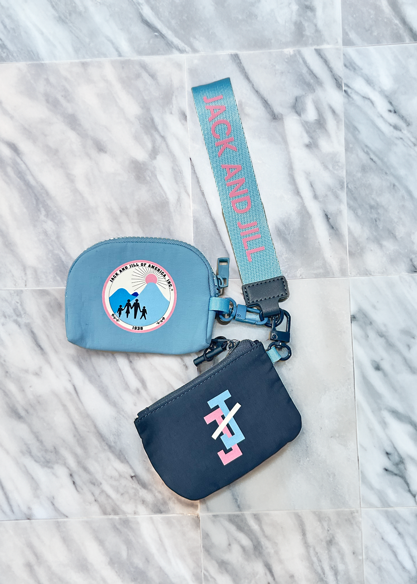 Two small blue wristlet pouches with straps for jack and jill teens on a marble surface, featuring 'Jack and Jill' logos