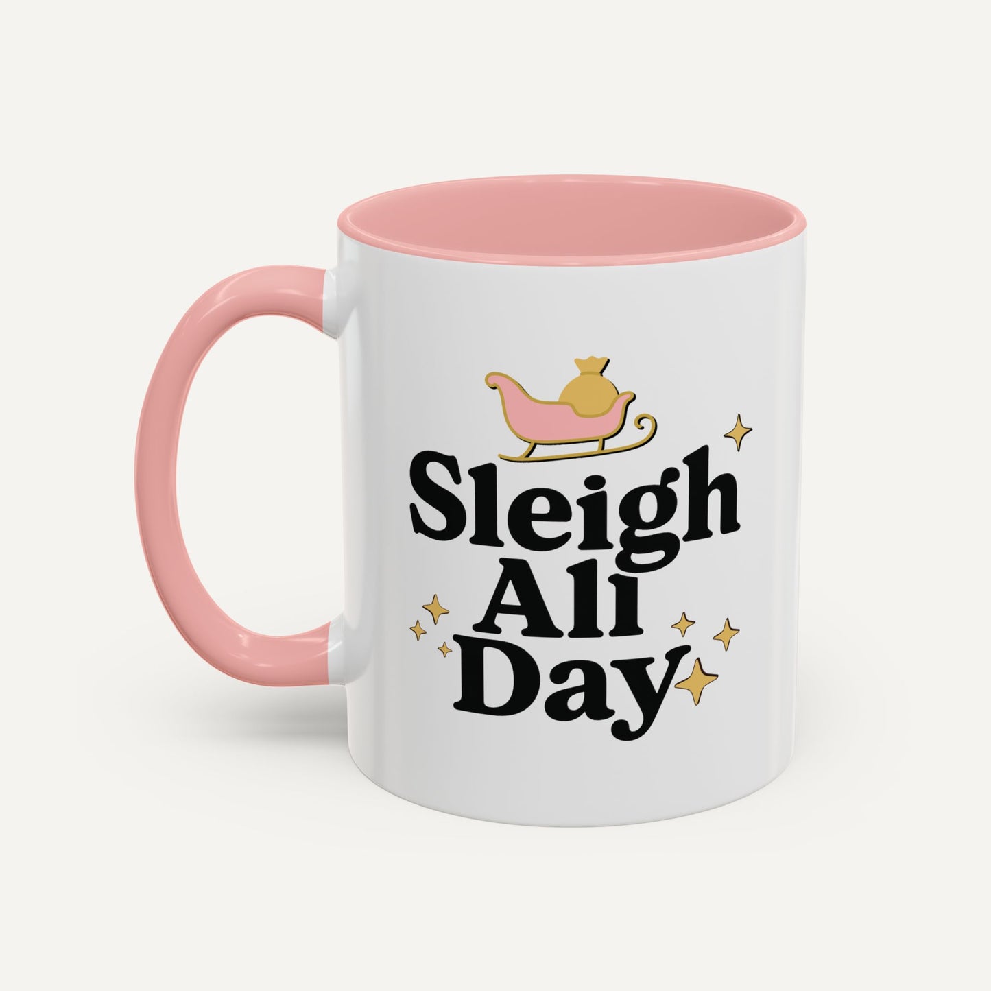 White mug with pink interior and handle, featuring 'Sleigh All Day' text and a sleigh illustration.