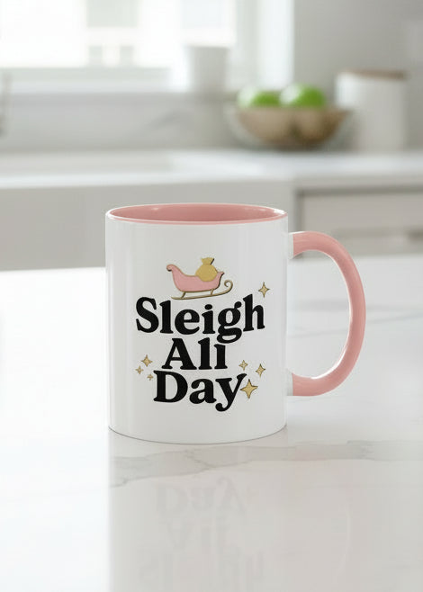 White mug with pink interior and handle featuring 'Sleigh All Day' text and sleigh graphic.
